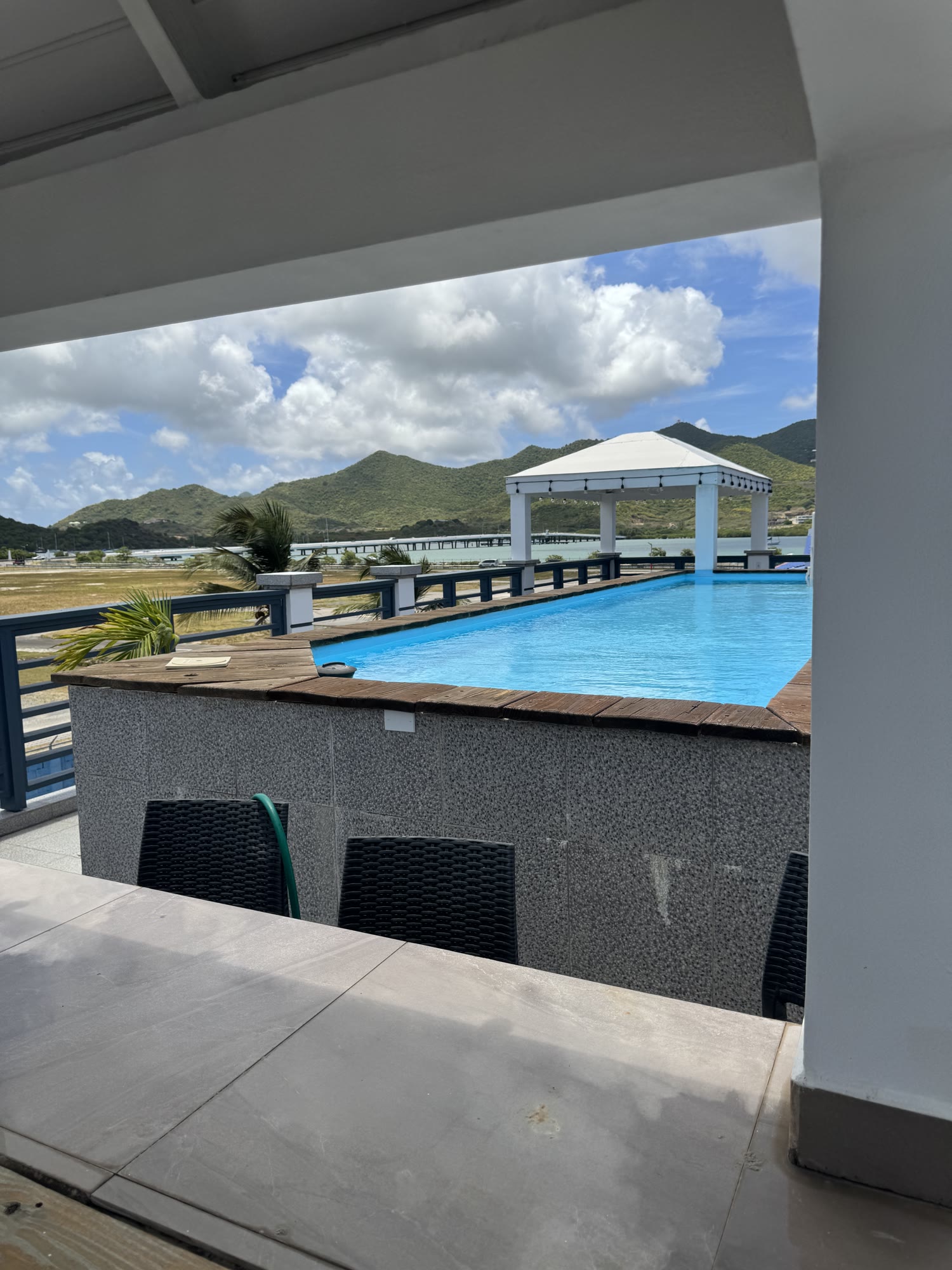 The rooftop pool deck with deep wicker loungers, the lap pool and the gazebo beyond — where delegates step out between sessions